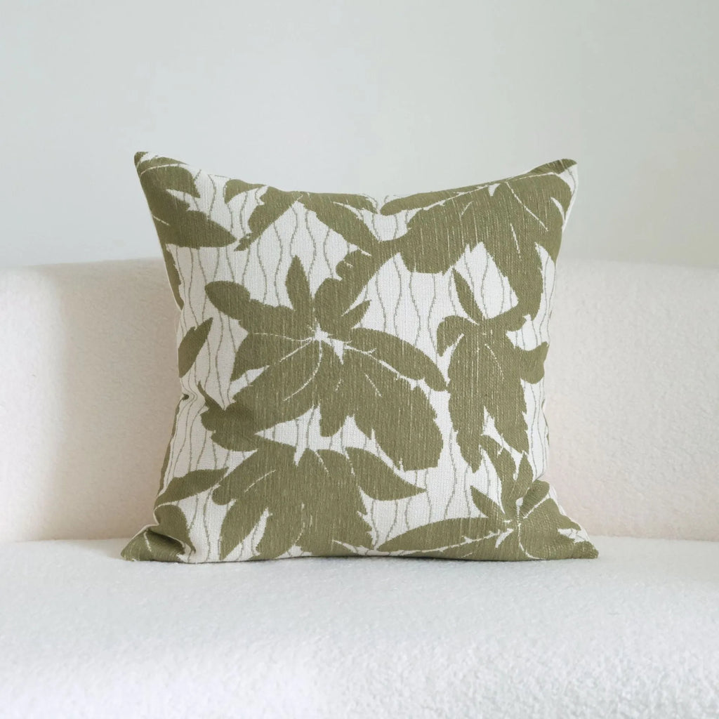 Green cotton and linen hotel sample pillow with botanical pattern and tassel detail on a display bed.