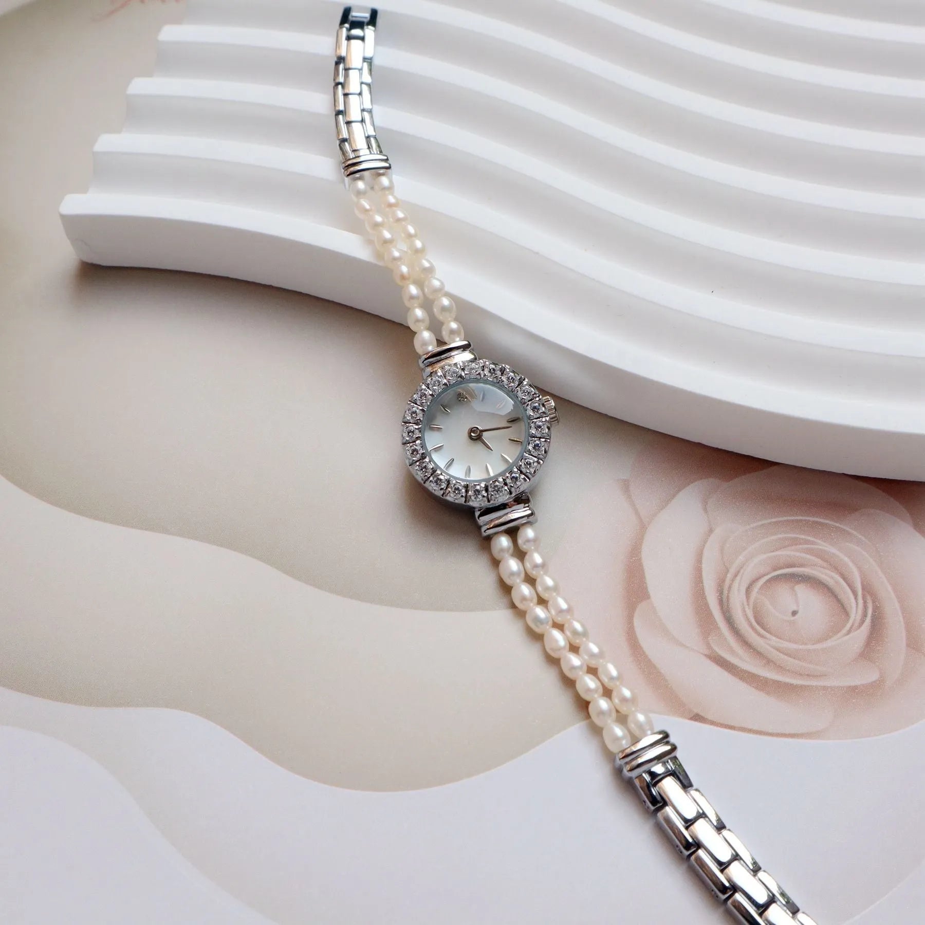 Women's light gold bracelet watch with a freshwater pearl charm and round mineral glass dial.