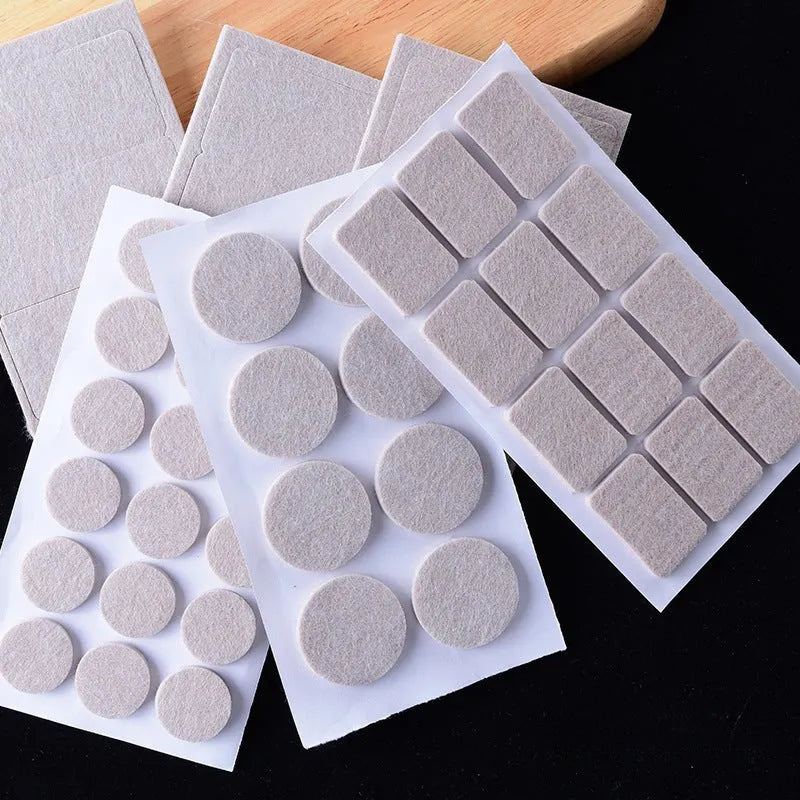 Assortment of beige round and square plastic non-slip furniture foot pads on a wooden floor.
