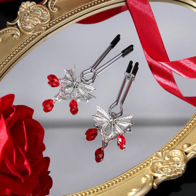 Silver alloy bat-themed nipple clamp with adjustable pressure and a red ruby decorative clip.