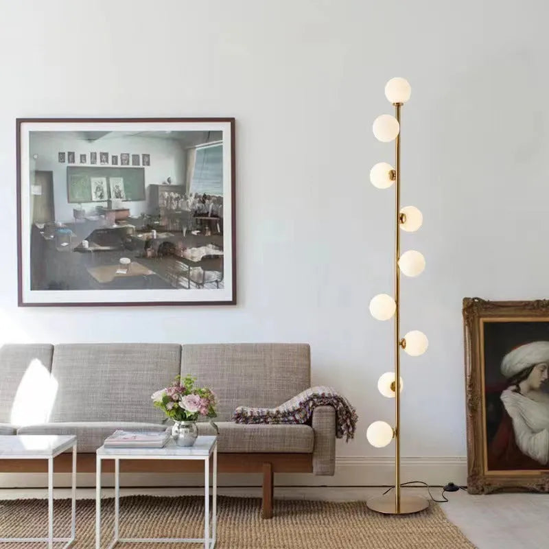 Tall modern floor lamp with glass shade and ironwork base on a wooden floor, showing minimalist Nordic design.