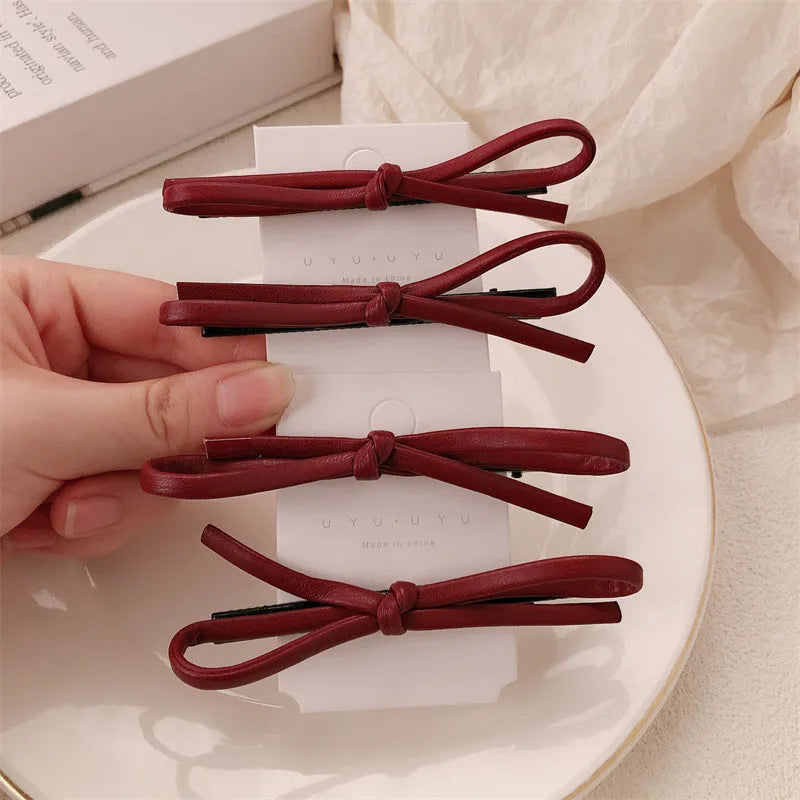 Wine red genuine leather bow hair barrette with a 6cm long metal clip on a white background.