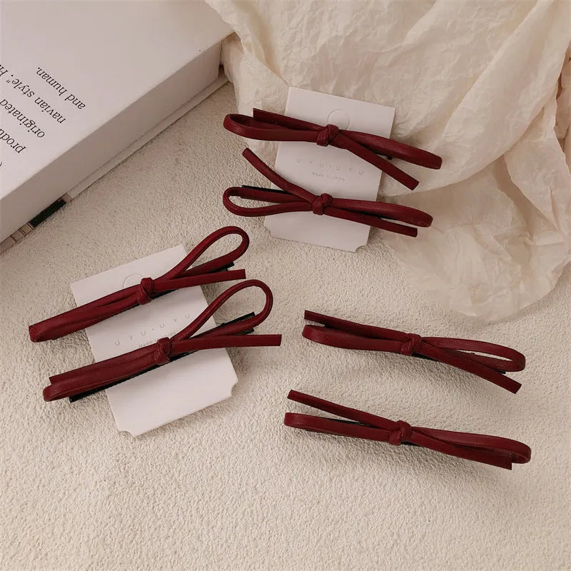 Wine red genuine leather bow hair barrette with a 6cm long metal clip on a white background.