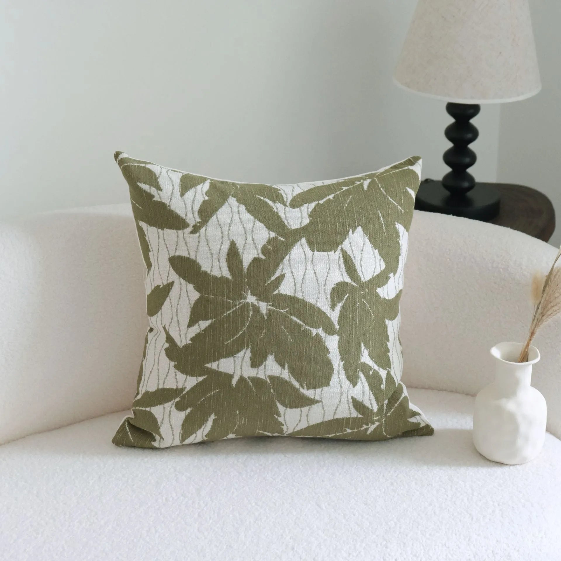 Green cotton and linen hotel sample pillow with botanical pattern and tassel detail on a display bed.
