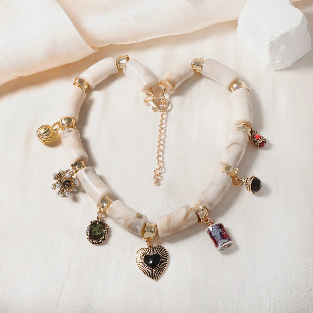 Bamboo-shaped resin pendant necklace with heart charm and electroplated finish.