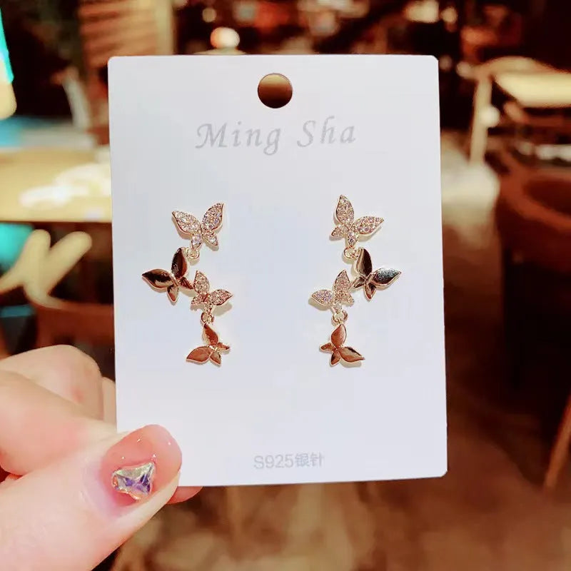 Gold tone butterfly drop earrings with four copper charms on each piece for women