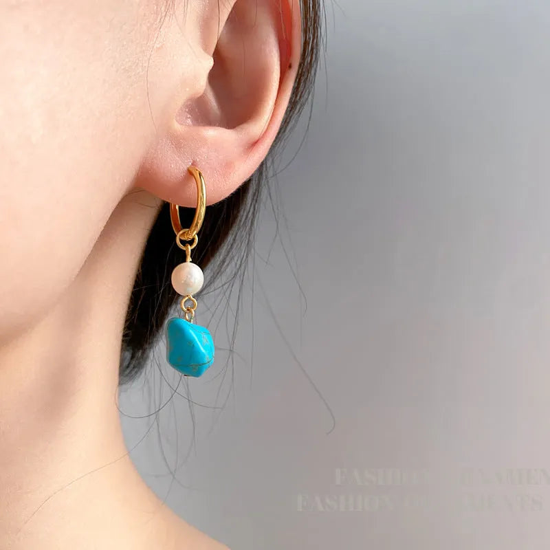A pair of long dangle earrings with an irregular turquoise geometric clip and a cultured pearl drop on a copper setting.