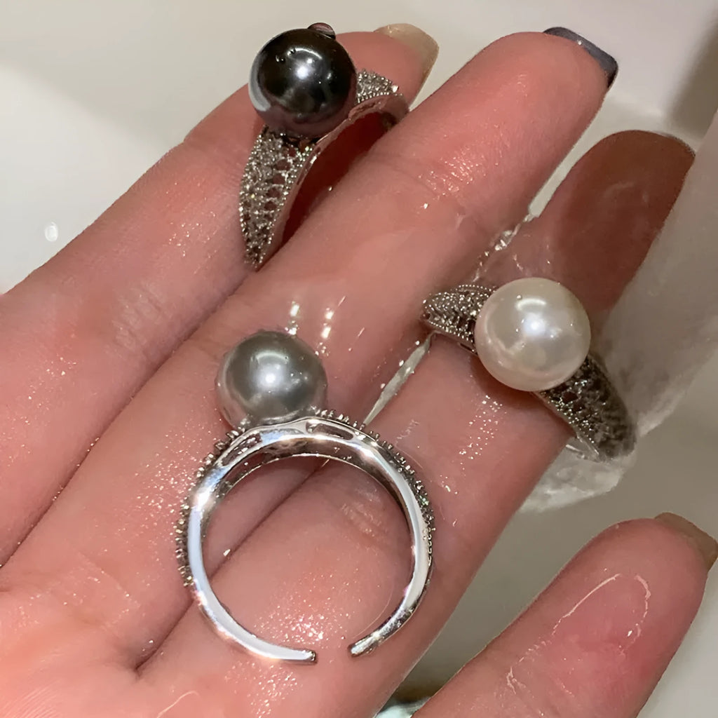 Geometric copper open ring with a black pearl on a model's finger.