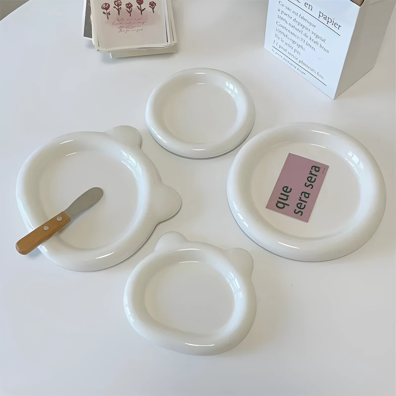 White porcelain plate with doodle design, shown in round and bear shapes, small and large sizes.