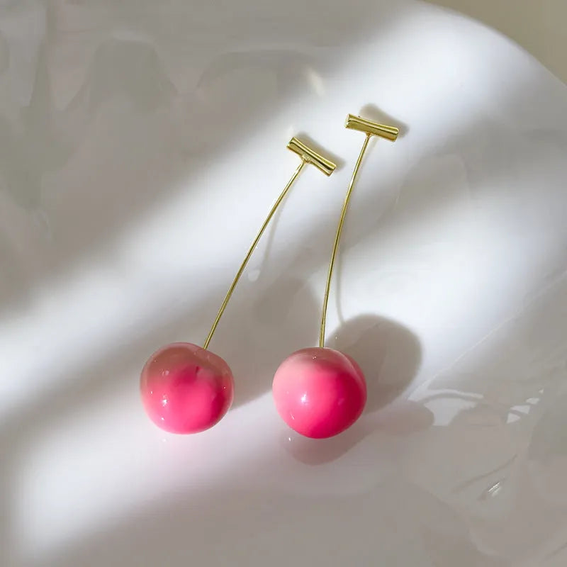 A pair of peach-shaped acrylic earrings on copper studs, shown in small and large size options.