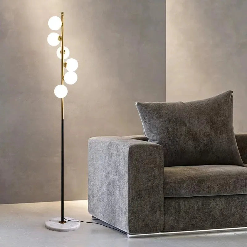 Tall modern floor lamp with glass shade and ironwork base on a wooden floor, showing minimalist Nordic design.