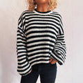 Woman wearing a black and white striped loose pullover sweater with a round neck and long sleeves.