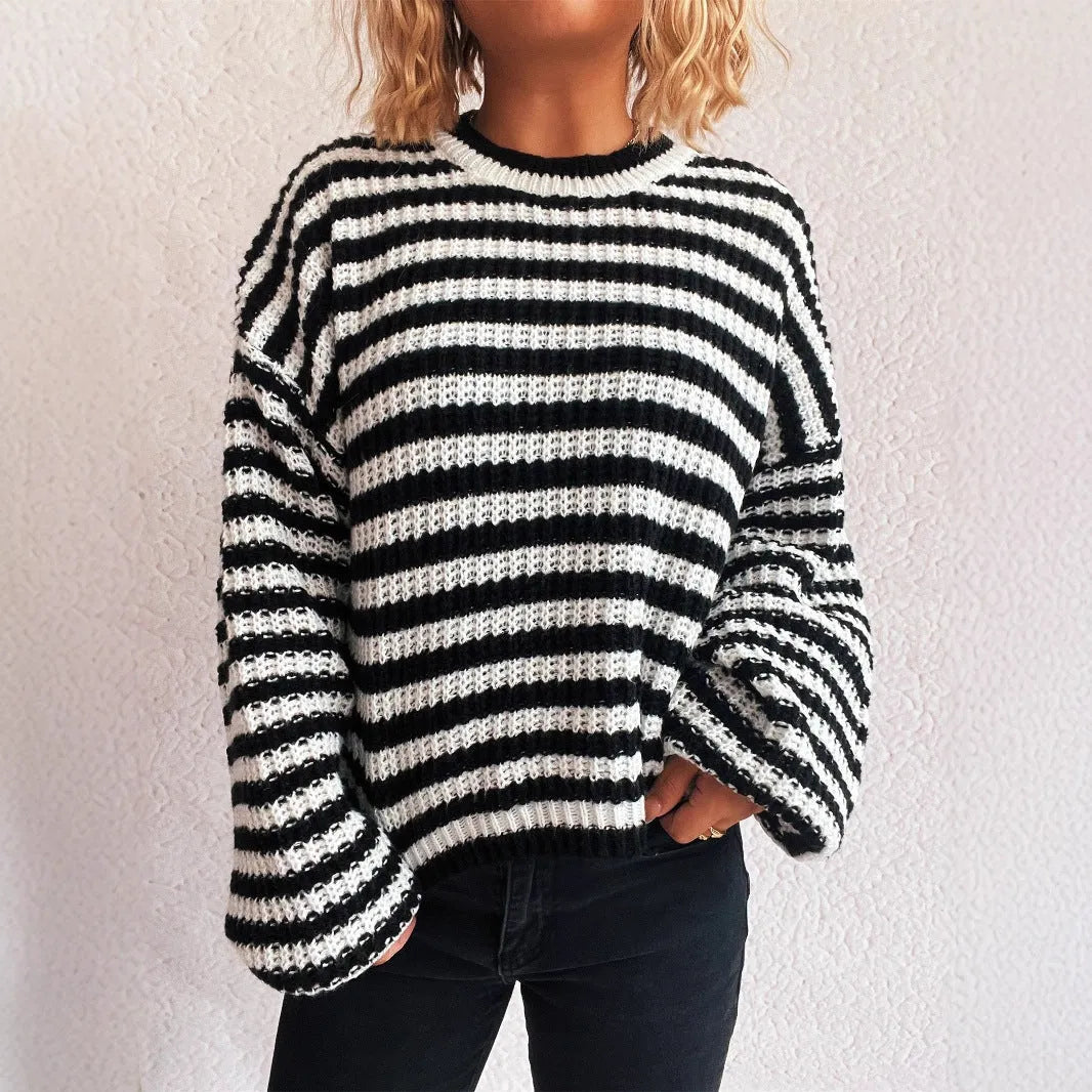 Woman wearing a black and white striped loose pullover sweater with a round neck and long sleeves.