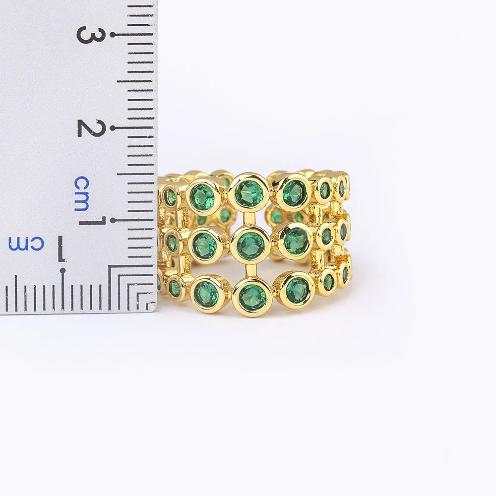 Copper ring with gold plating showing three-layer green stone setting and zircon detailing on wide band.