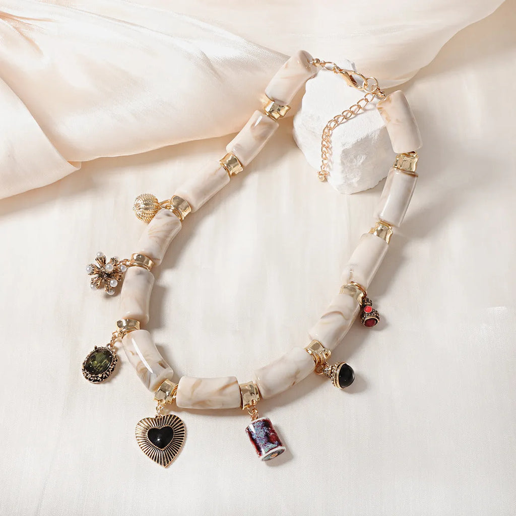 Bamboo-shaped resin pendant necklace with heart charm and electroplated finish.