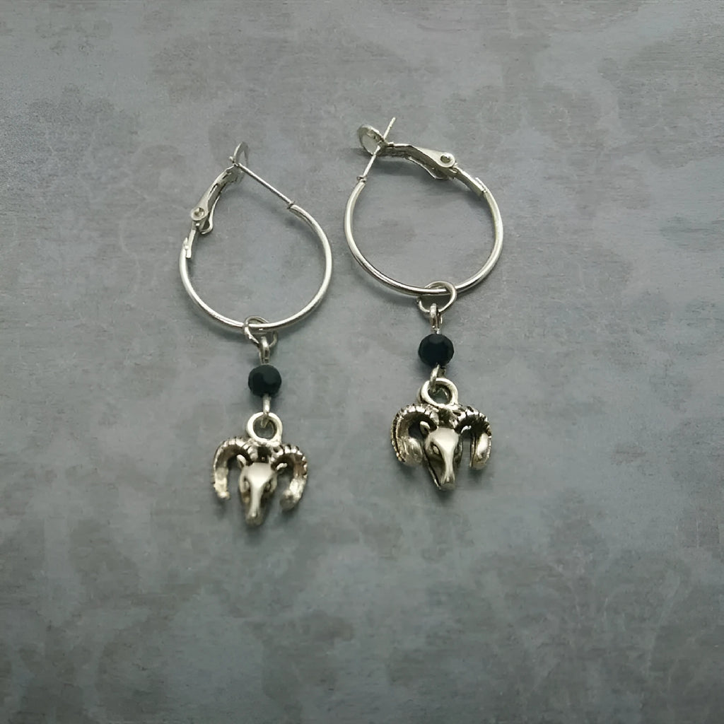 A pair of silver-coloured alloy round earrings featuring a Tibetan antelope design motif.