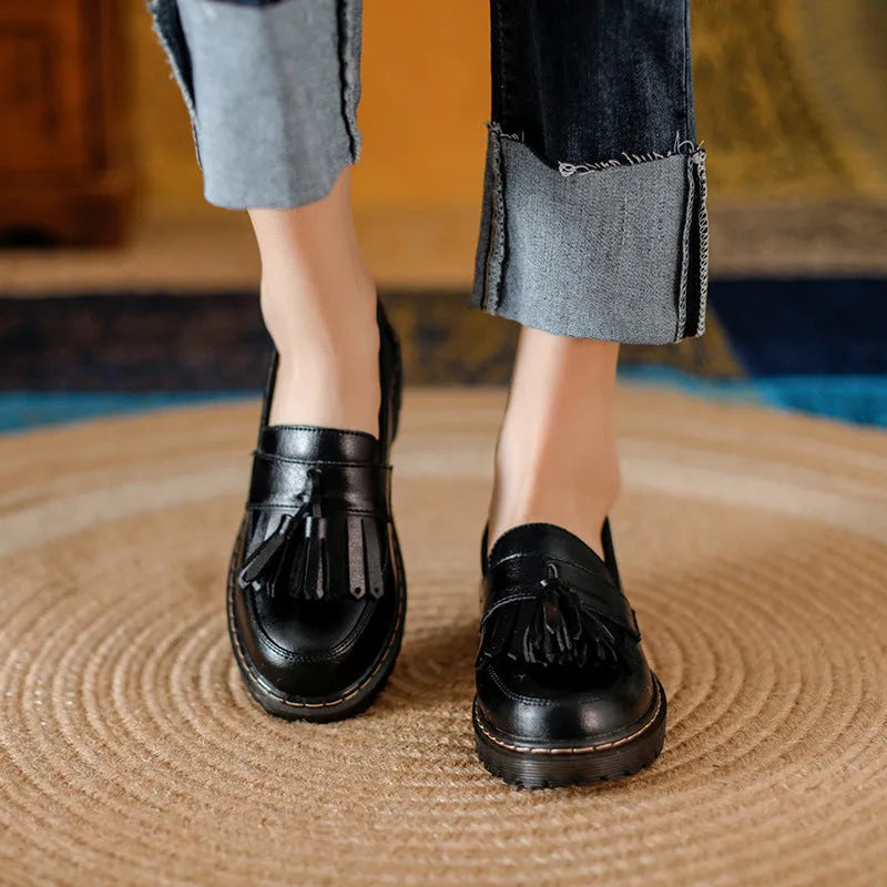 Women's brown leather loafers with tassel detail and a low chunky heel.