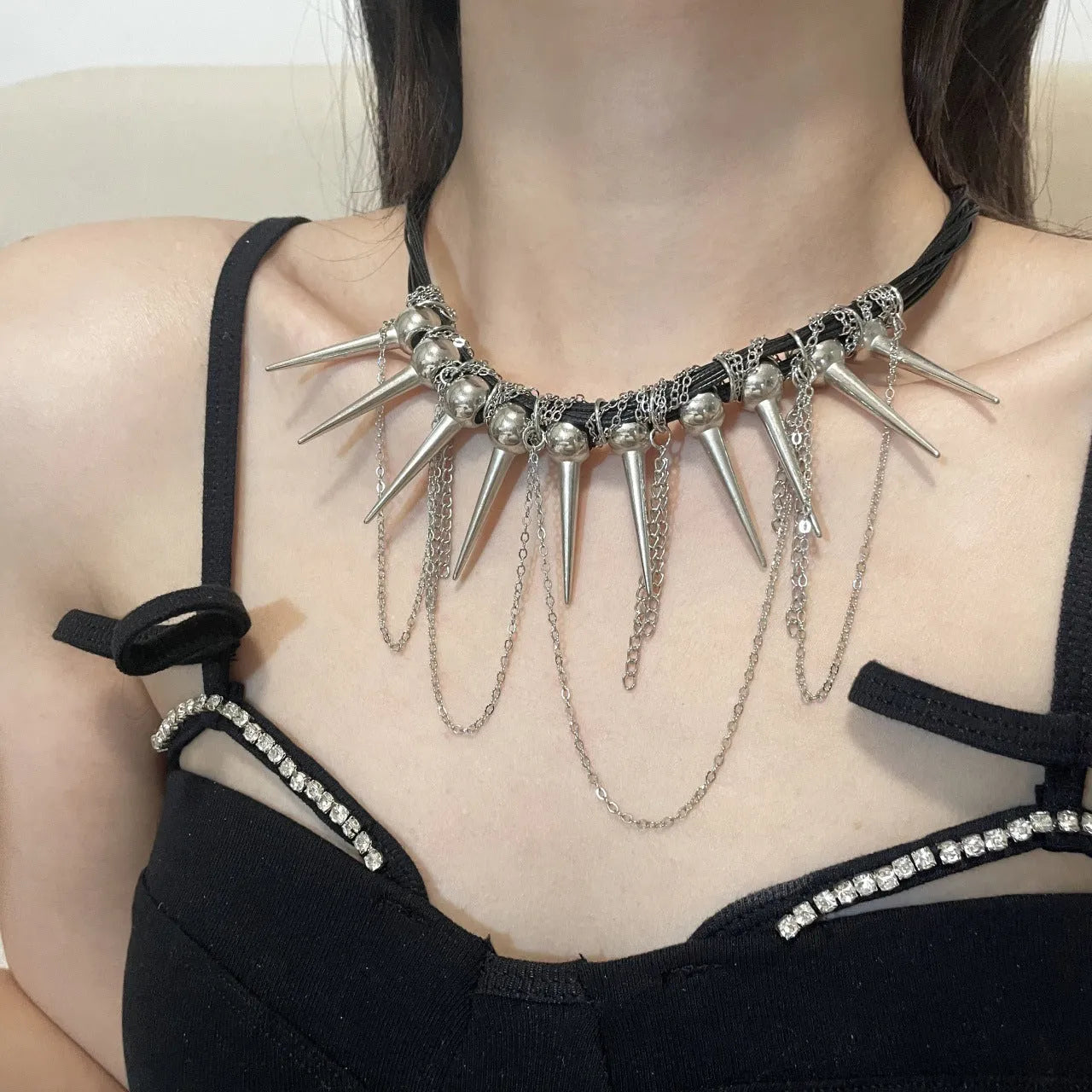 Leather necklace with electroplated round beads, winding design, tassel, and point rivet details.