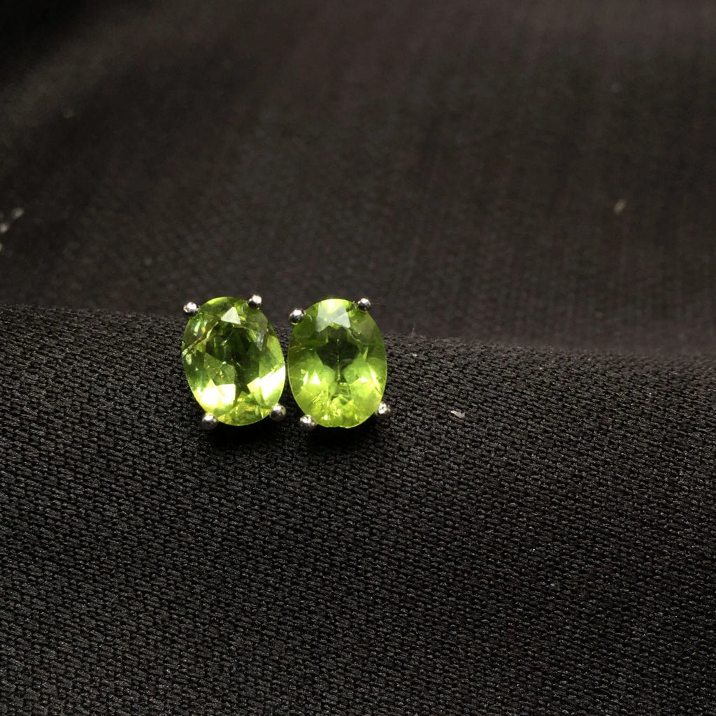 Close-up of natural grass green olivine stud earrings in sterling silver geometric setting.