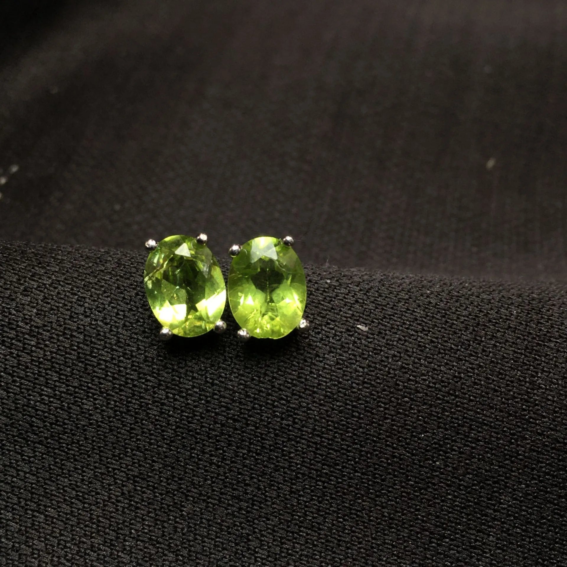 Close-up of natural grass green olivine stud earrings in sterling silver geometric setting.