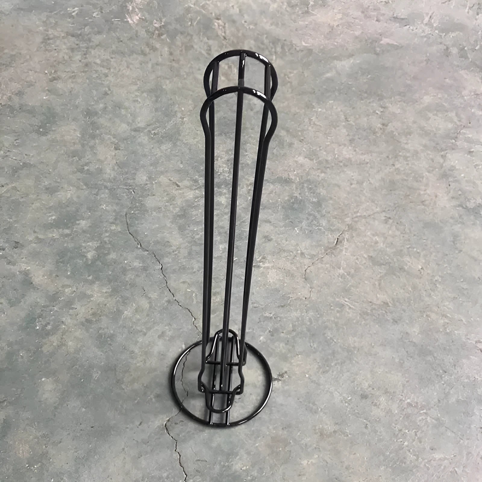 Black and silver wrought iron coffee capsule storage rack holding pods on shelves.
