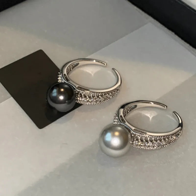 Geometric copper open ring with a black pearl on a model's finger.