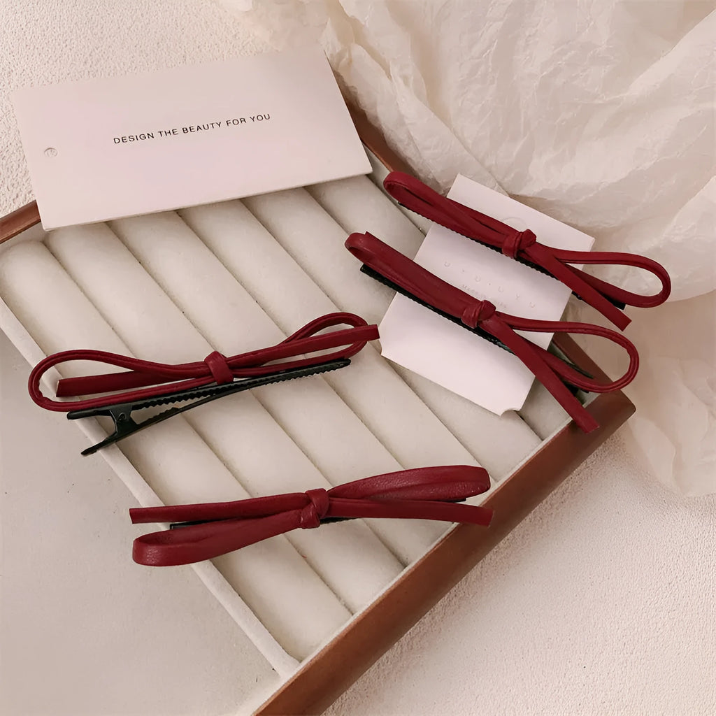 Wine red genuine leather bow hair barrette with a 6cm long metal clip on a white background.