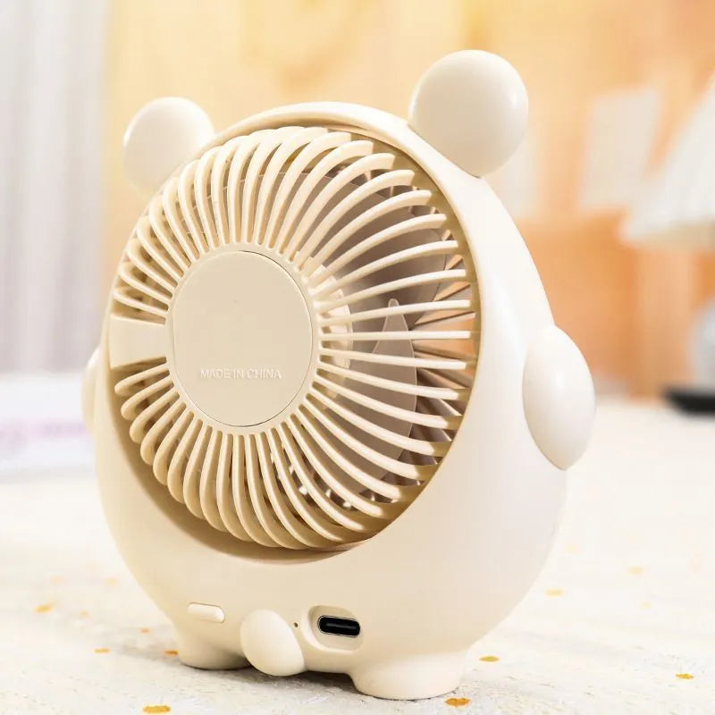Cute dog-shaped desktop USB fan in a choice of colours on a wooden desk.