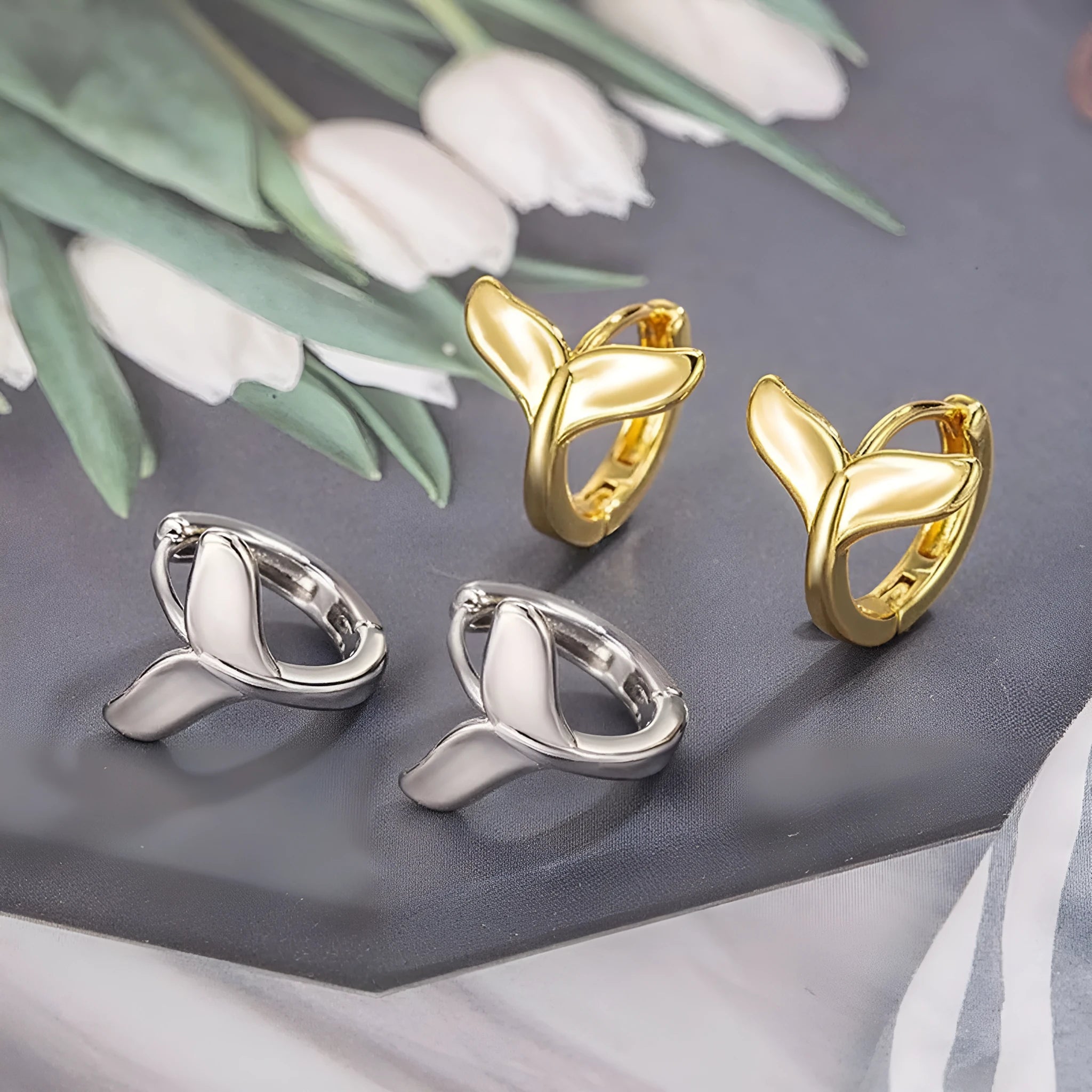 A pair of simple women's fishtail earrings with an electroplated metallic finish.