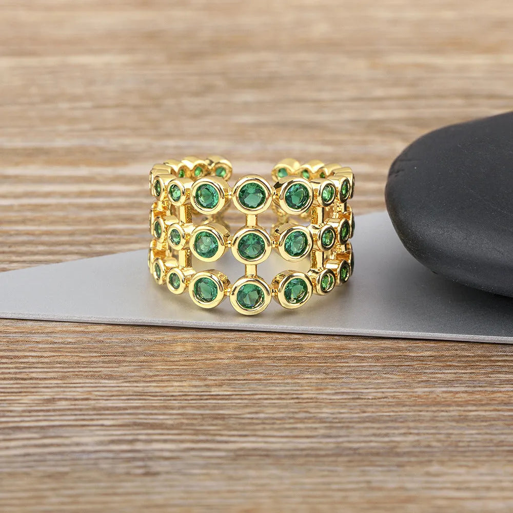 Copper ring with gold plating showing three-layer green stone setting and zircon detailing on wide band.