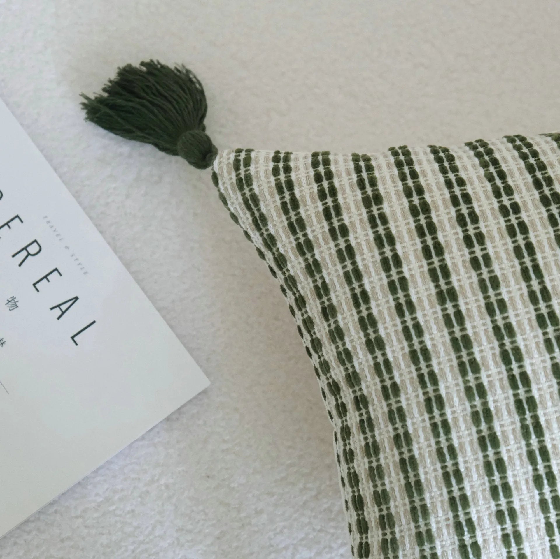 Green cotton and linen hotel sample pillow with botanical pattern and tassel detail on a display bed.