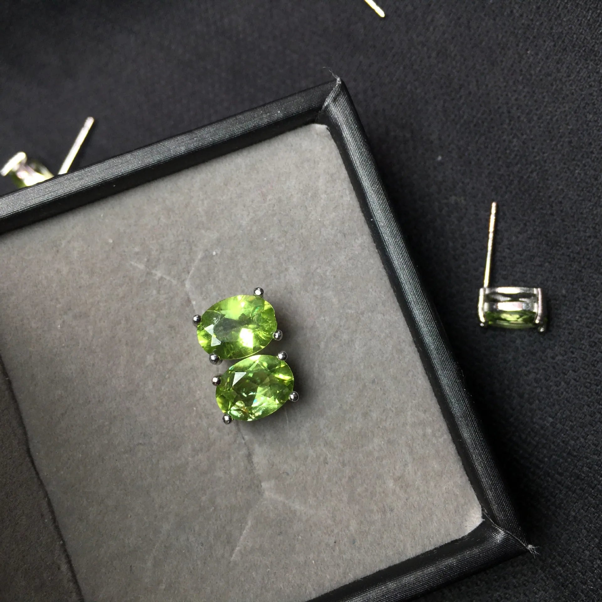 Close-up of natural grass green olivine stud earrings in sterling silver geometric setting.