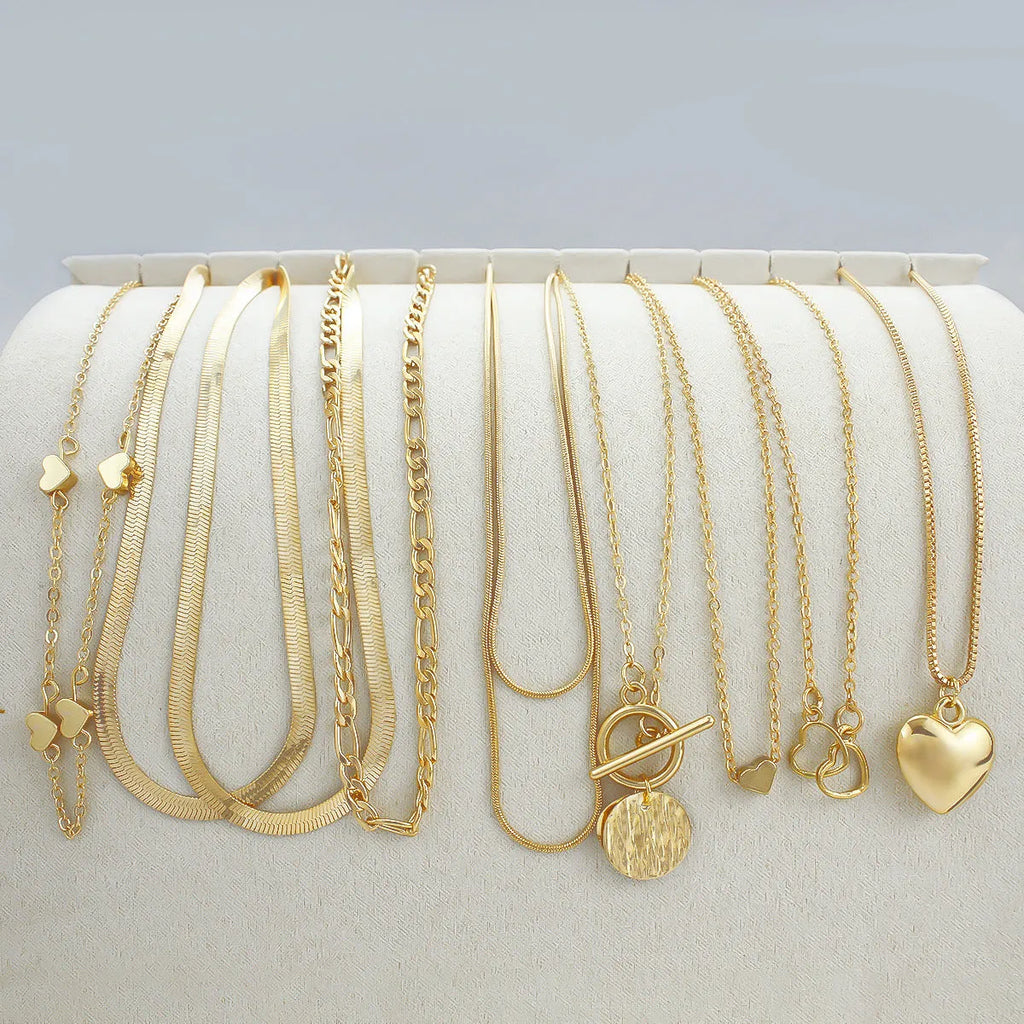 Ten gold necklaces with snake bone chains and alloy pendants displayed as complete jewellery set