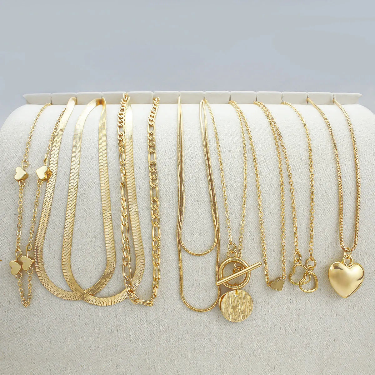 Ten gold necklaces with snake bone chains and alloy pendants displayed as complete jewellery set