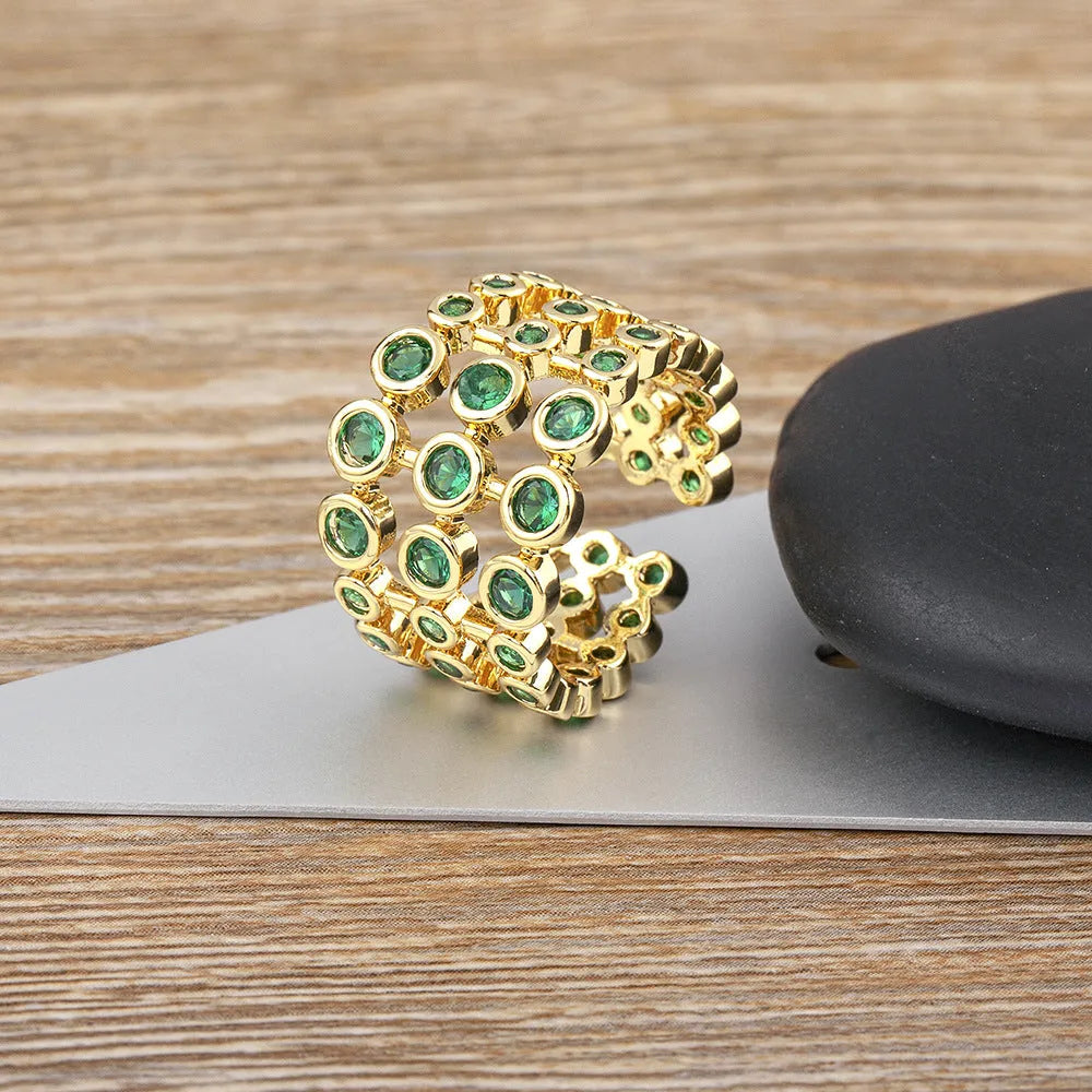 Copper ring with gold plating showing three-layer green stone setting and zircon detailing on wide band.