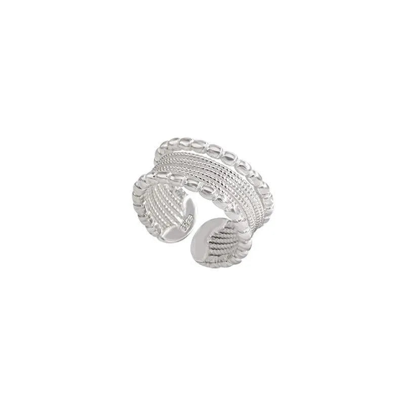 Geometric woven twisted copper alloy ring with an adjustable opening on a neutral background.