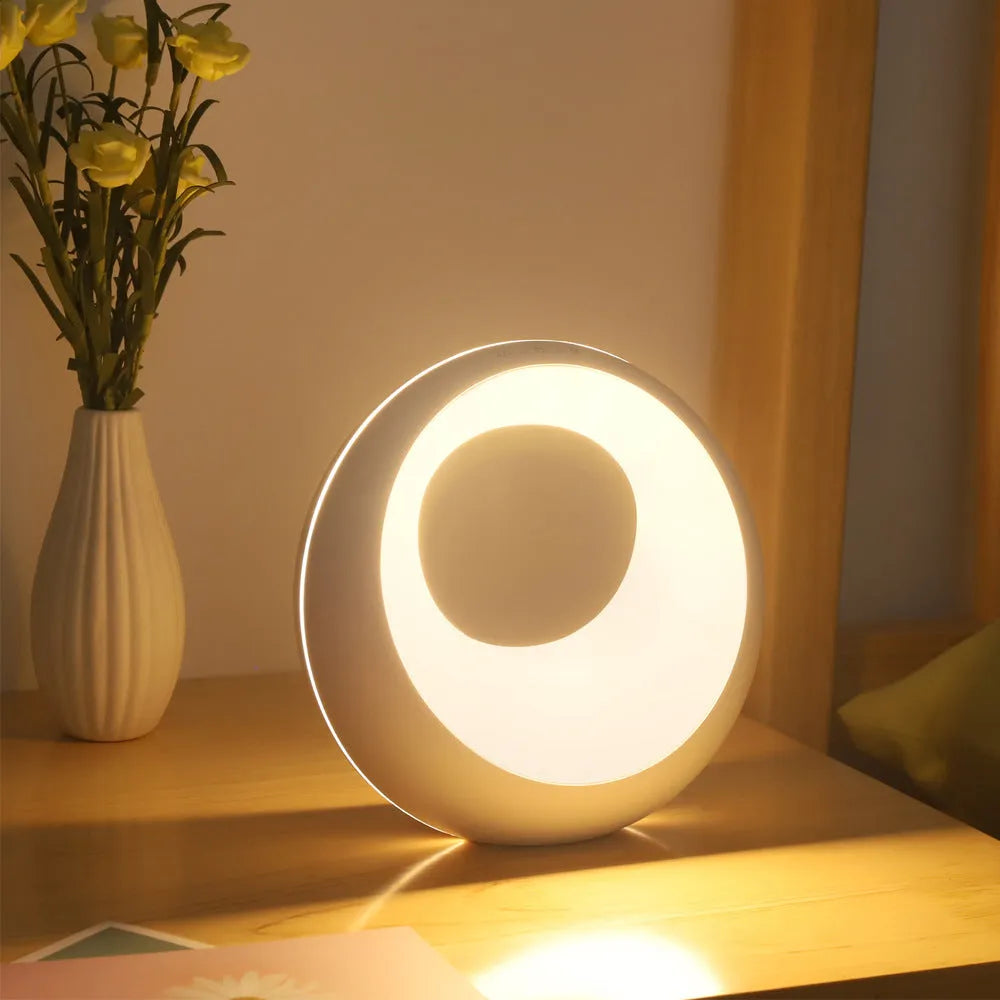Small white desk lamp with remote control showing RGB colour-changing illumination on dark surface