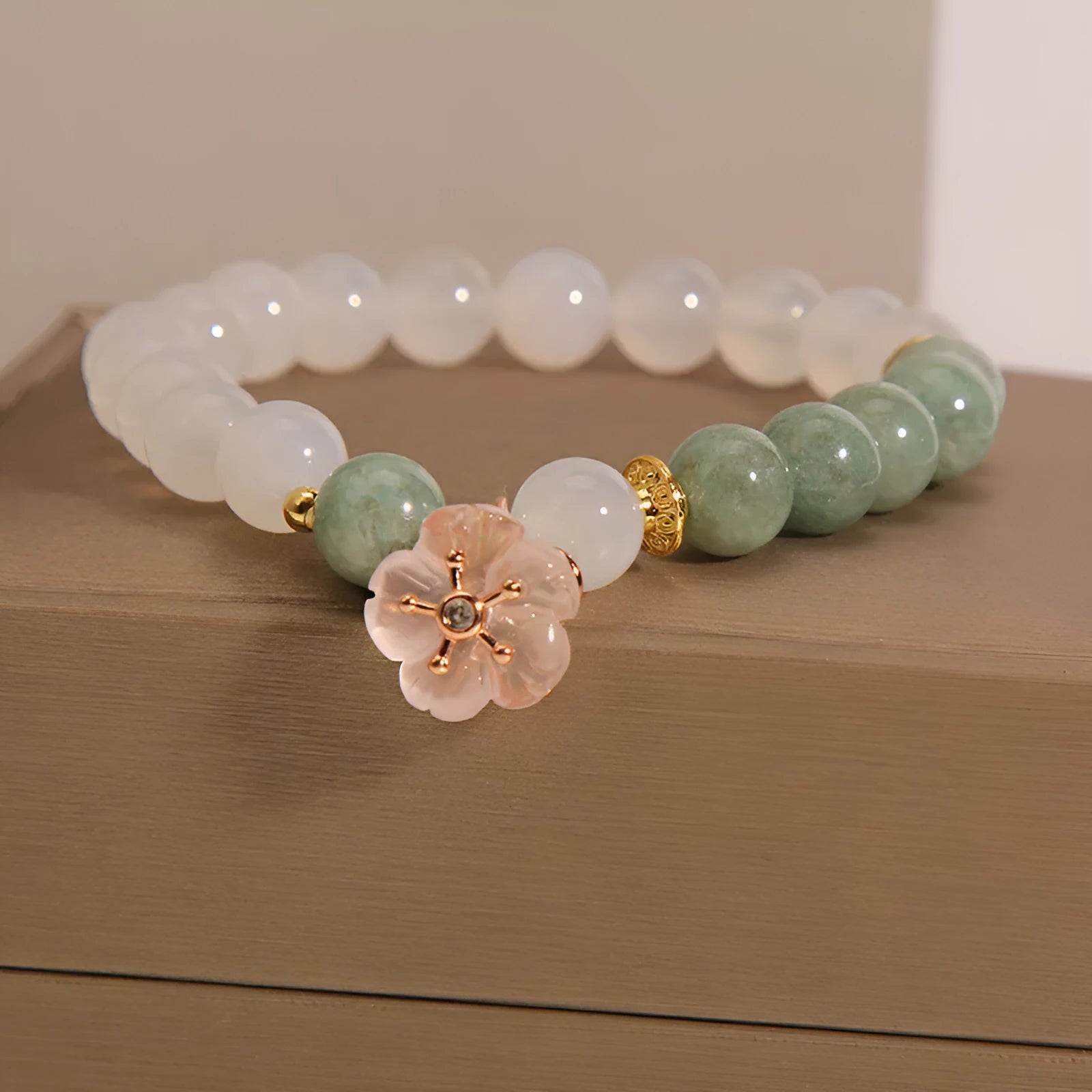 White agate jade flower bracelet with pink accent stones on wrist