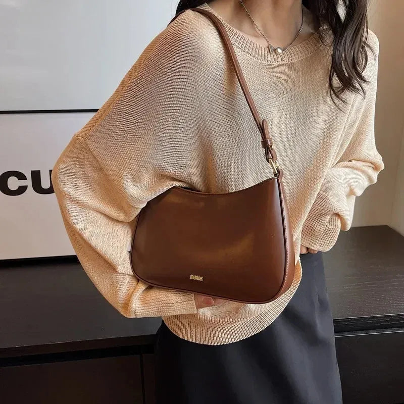 Red underarm shoulder bag in textured faux leather with adjustable strap for crossbody or sling wear