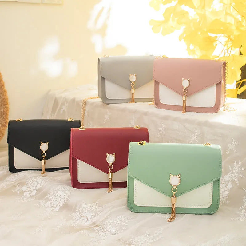 Small square PU leather messenger bag with cat tassel decoration and chain strap on a white background