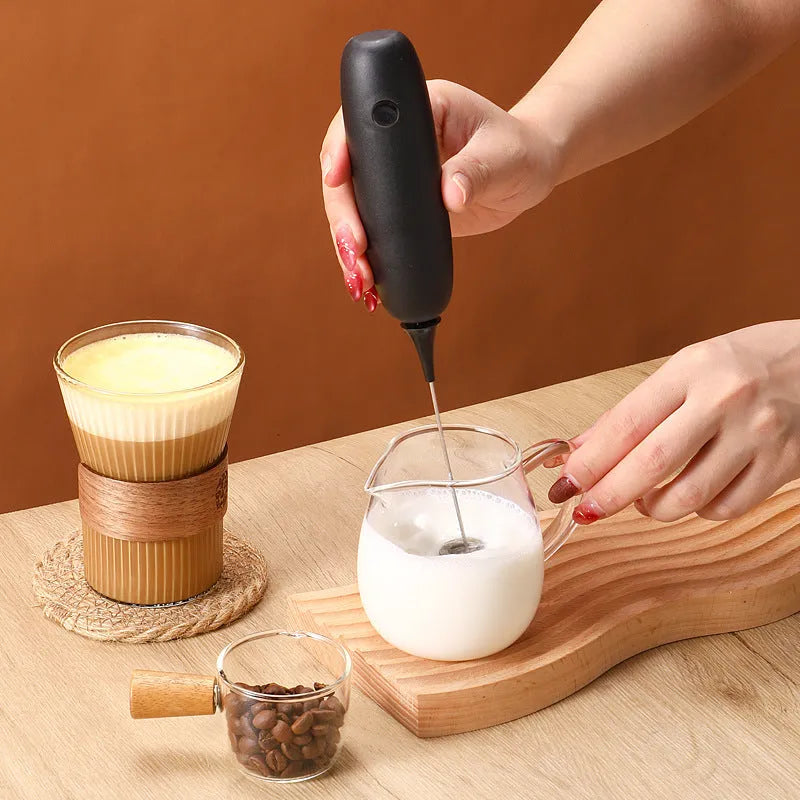 Black and white hand-held electric milk frother blender with modern design for coffee preparation