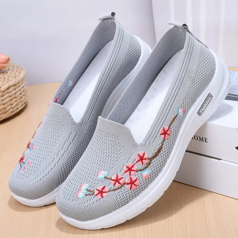 Women's embroidered floral flat pump in woven fabric with a low heel and round toe.
