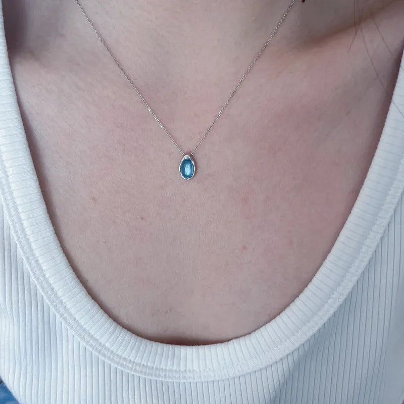 Geometric navy blue water drop pendant necklace on a platinum-colour adjustable cross chain.