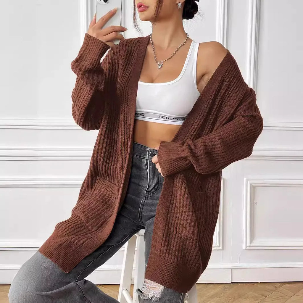 Women's dark green double pocket casual cardigan sweater laid flat.