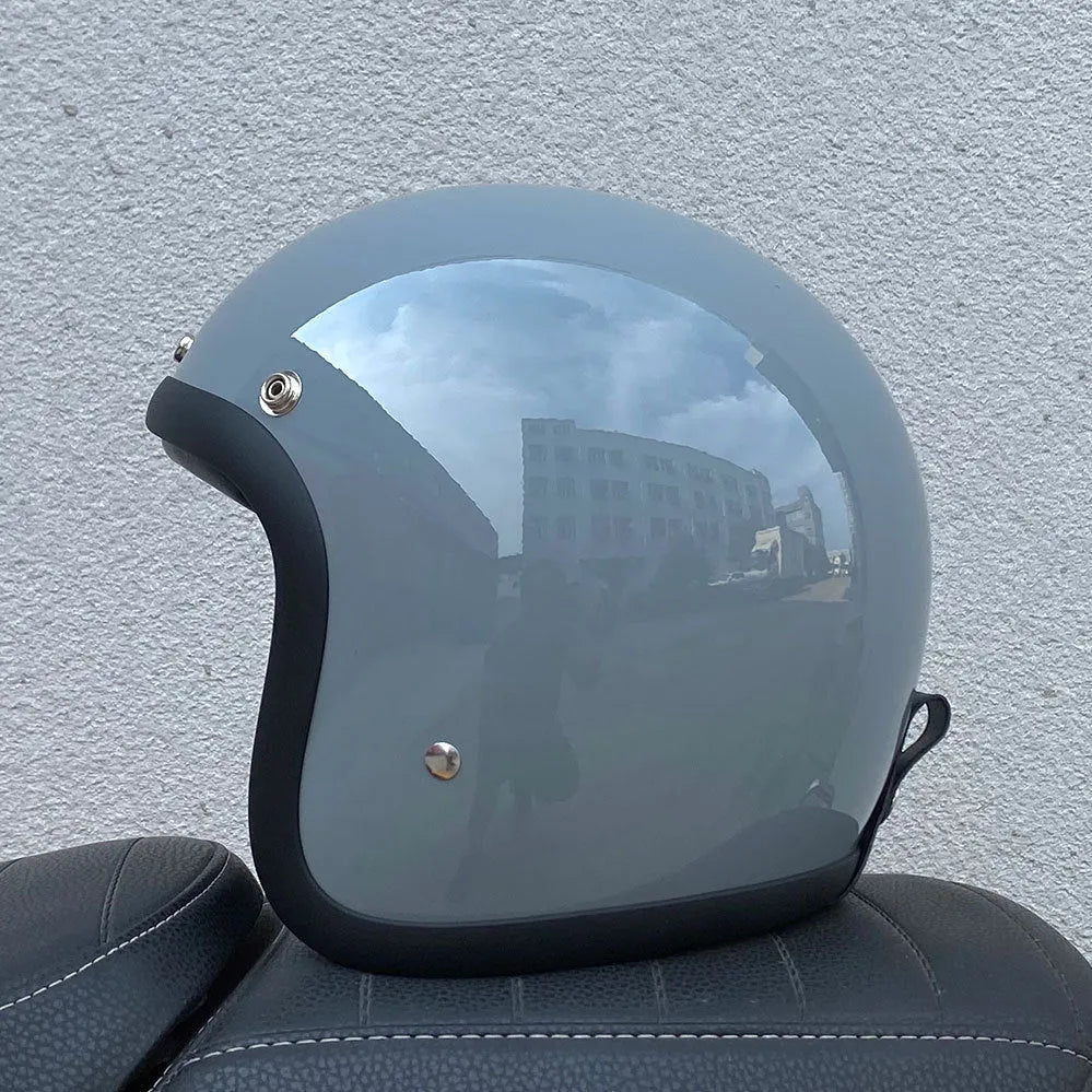 Retro-style open-face motorcycle helmet in matte black with floral design, showing clear visor and interior padding.