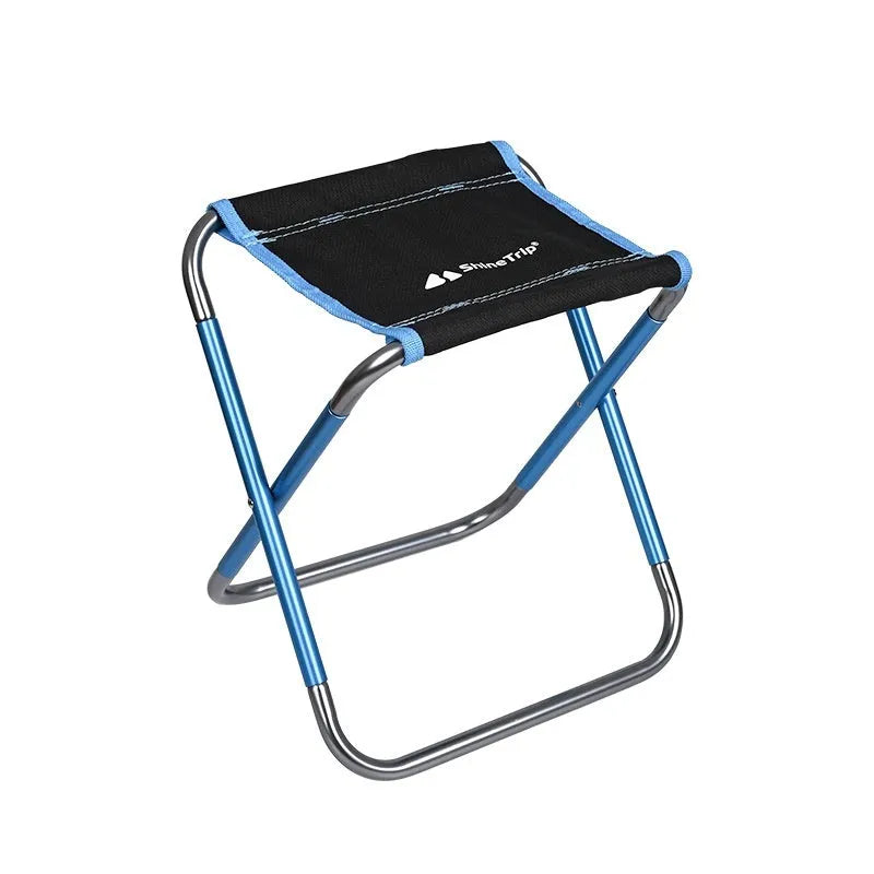 Black ethnic style aluminium alloy folding camping stool shown in use outdoors.