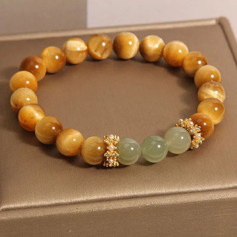 Natural yellow tiger's eye stone bracelet with gold gourd pattern on a white background.