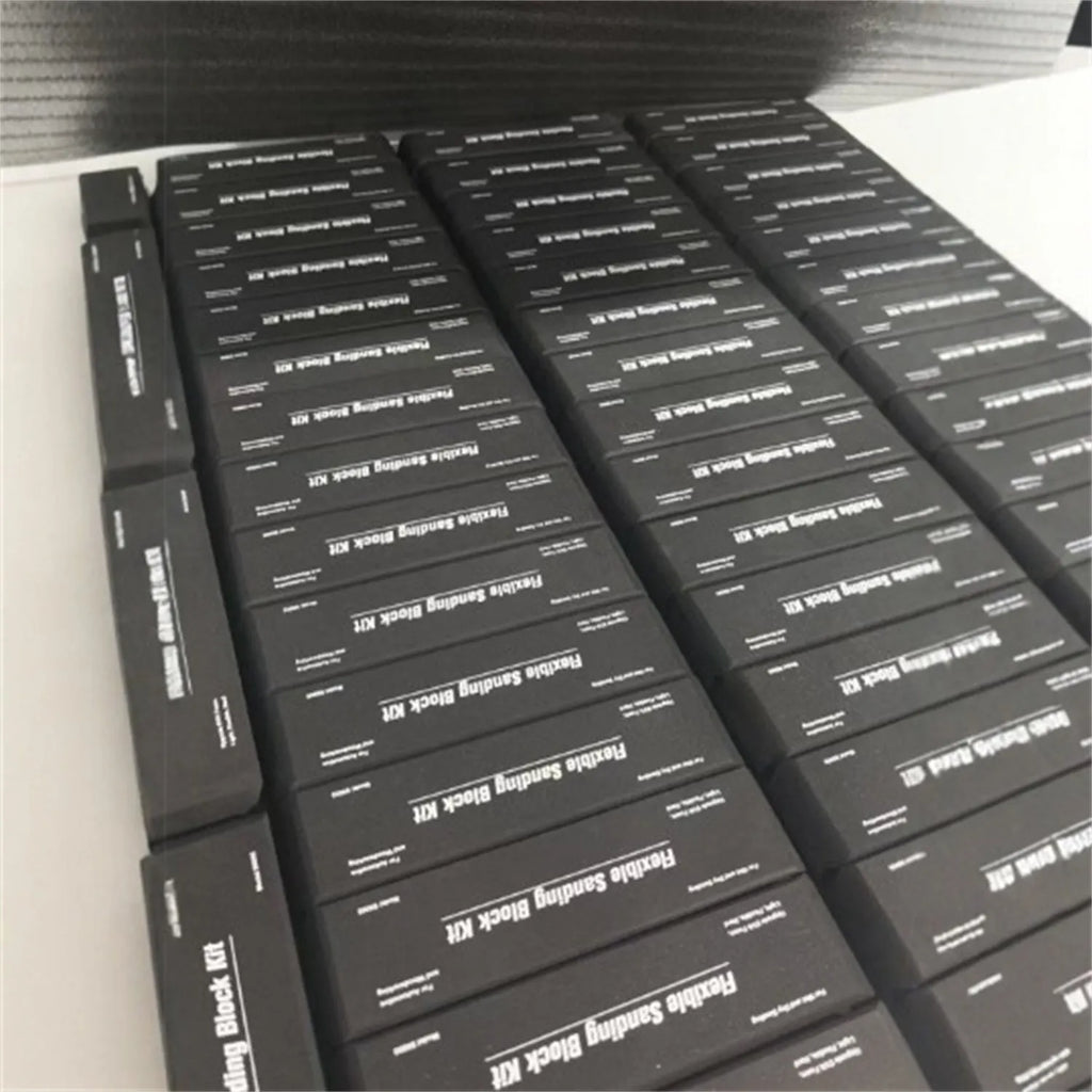 Seven black frosted metal building blocks arranged for architectural model assembly