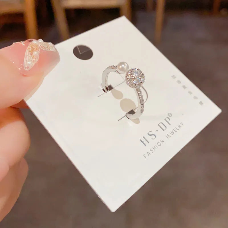 Gold or silver plated open-end pearl ring with round zircon stone on copper base.