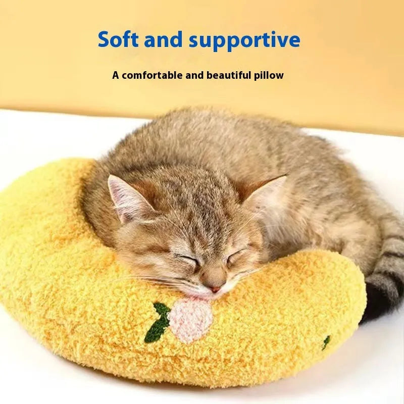 Blue U-shaped cat pillow with neck support in a moon design on a wooden floor.